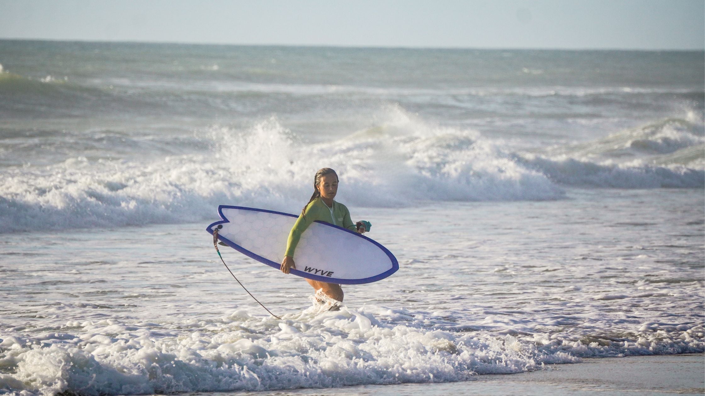 a surfer walking outsite of the wave with a fish surfboard from Wyve made from 3D printing technology 