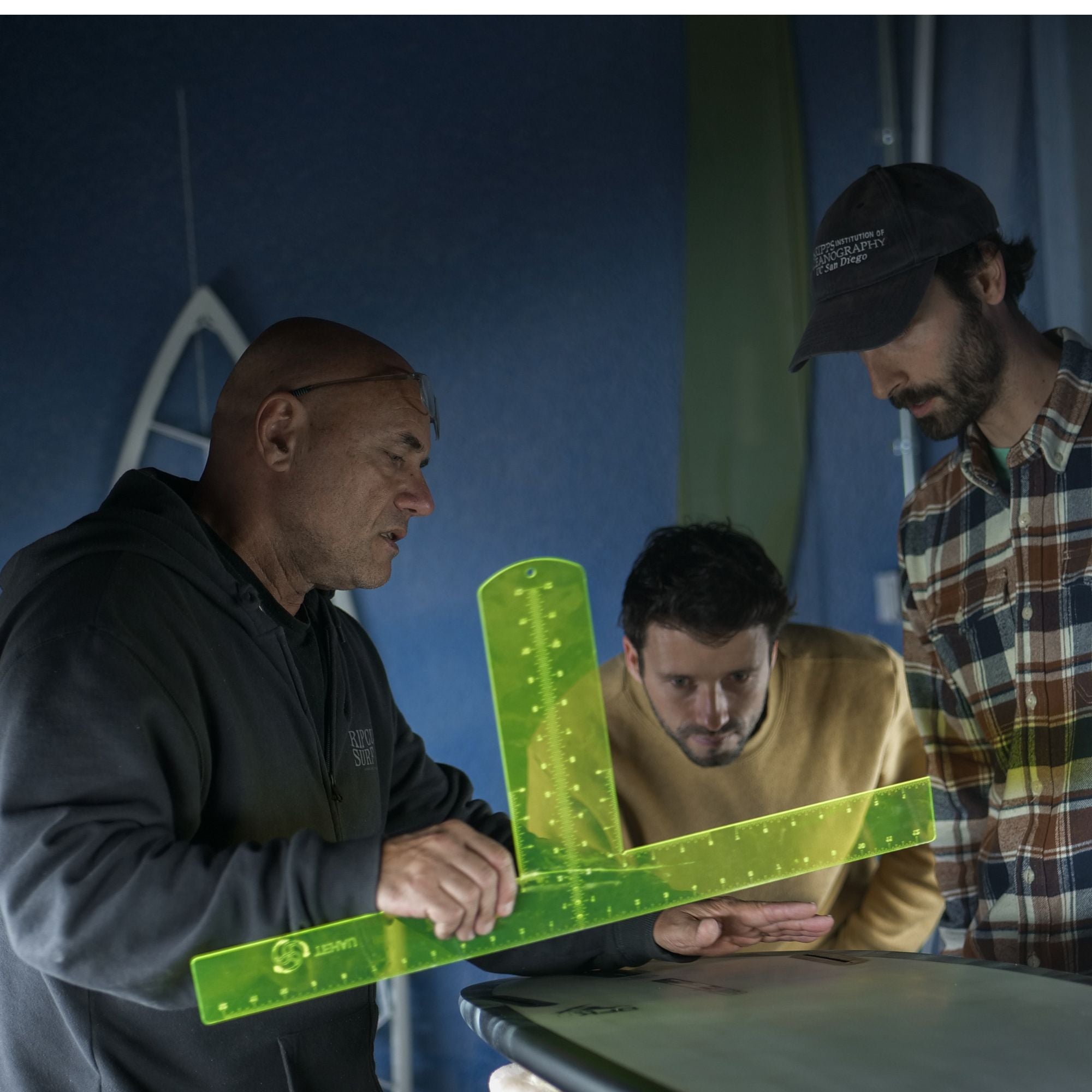 surfboard shaper  & wyve team looking at surfboard shape in a shapping room